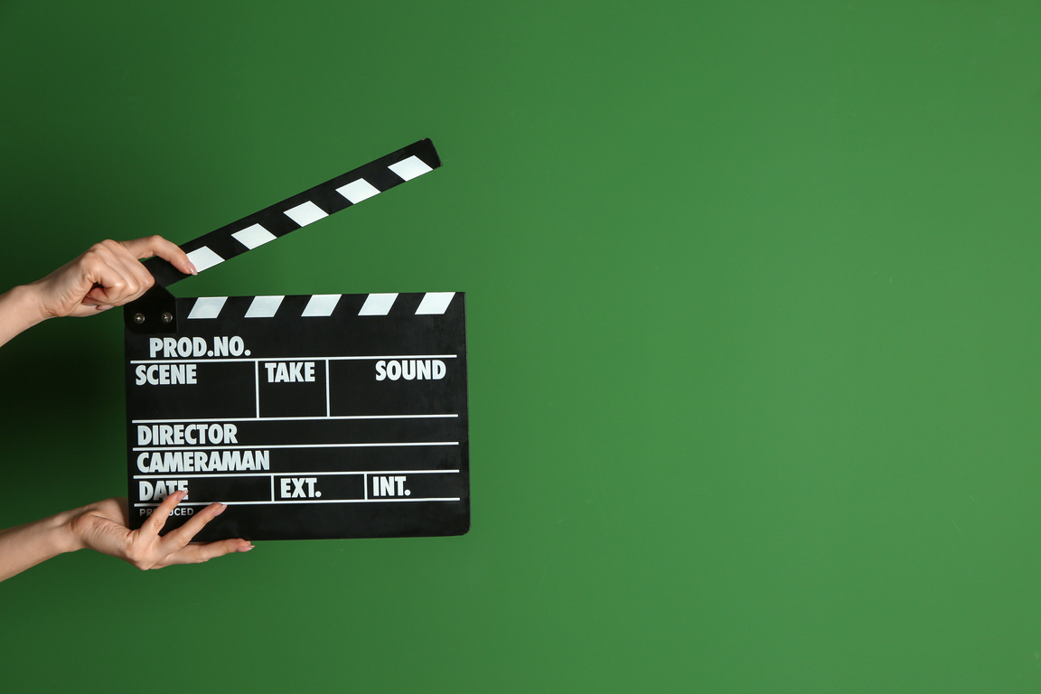 Female Hands with Cinema Clapperboard on Color Background